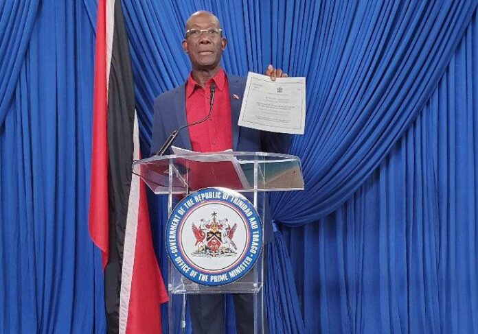 PM Dr Keith Rowley holds up copies of what he said was his Integrity Commission declaration forms during his press conference